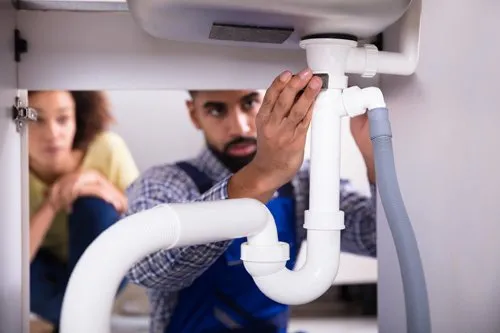 Lavabo altında tesisat tamiri yapan usta